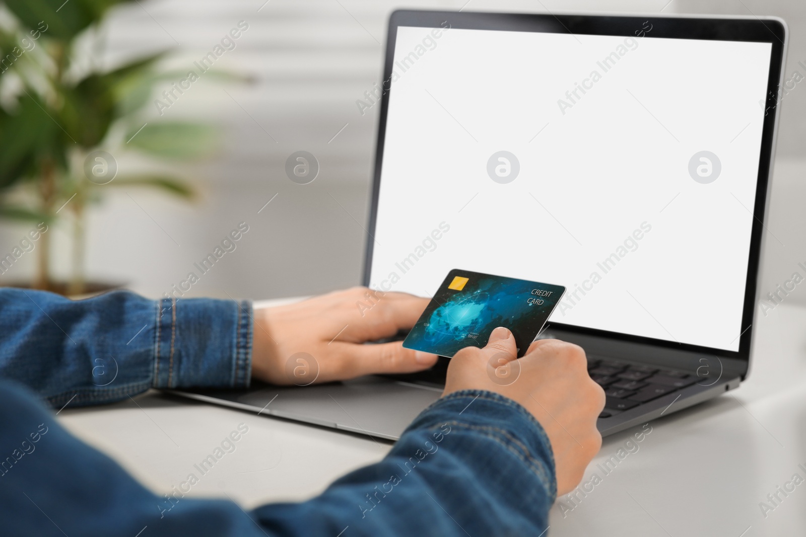 Photo of Woman with credit card using laptop at white table indoors, closeup