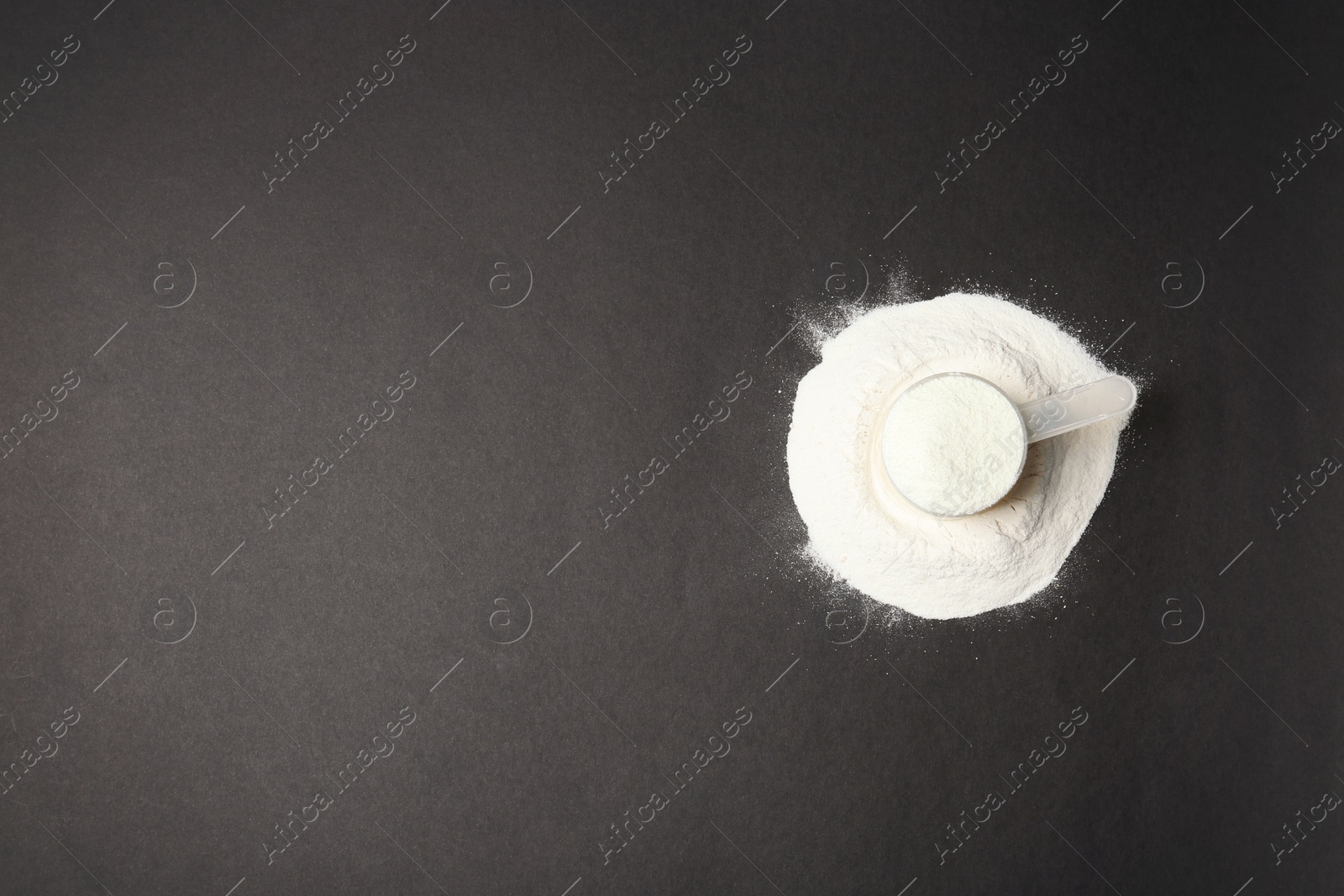 Photo of Pile of protein powder, scoop and space for text on black background, top view. Preparing shake