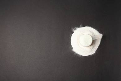 Photo of Pile of protein powder, scoop and space for text on black background, top view. Preparing shake