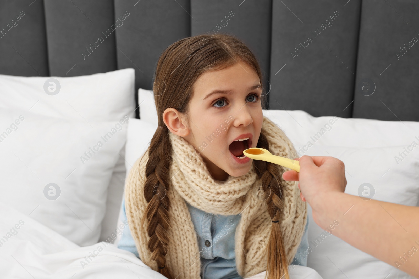 Photo of Mother giving cough syrup to her daughter at home