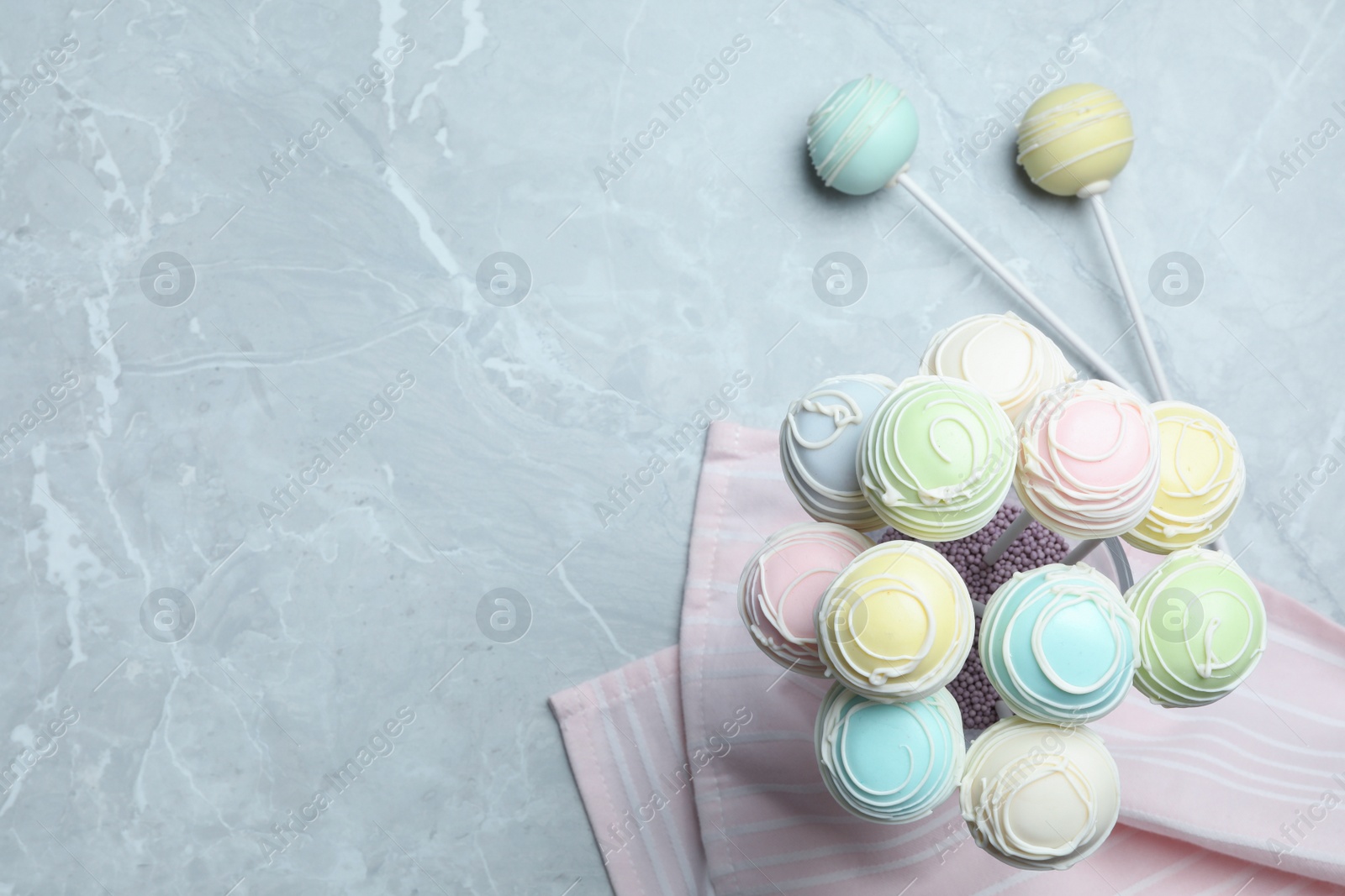 Photo of Sweet cake pops on grey marble table, flat lay. Space for text