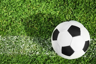 Photo of Soccer ball on fresh green football field grass, top view. Space for text