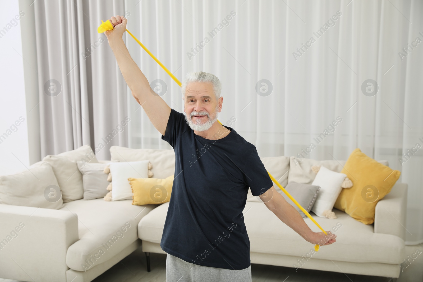 Photo of Senior man doing exercise with fitness elastic band at home