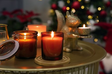 Burning candles on table in room decorated for Christmas