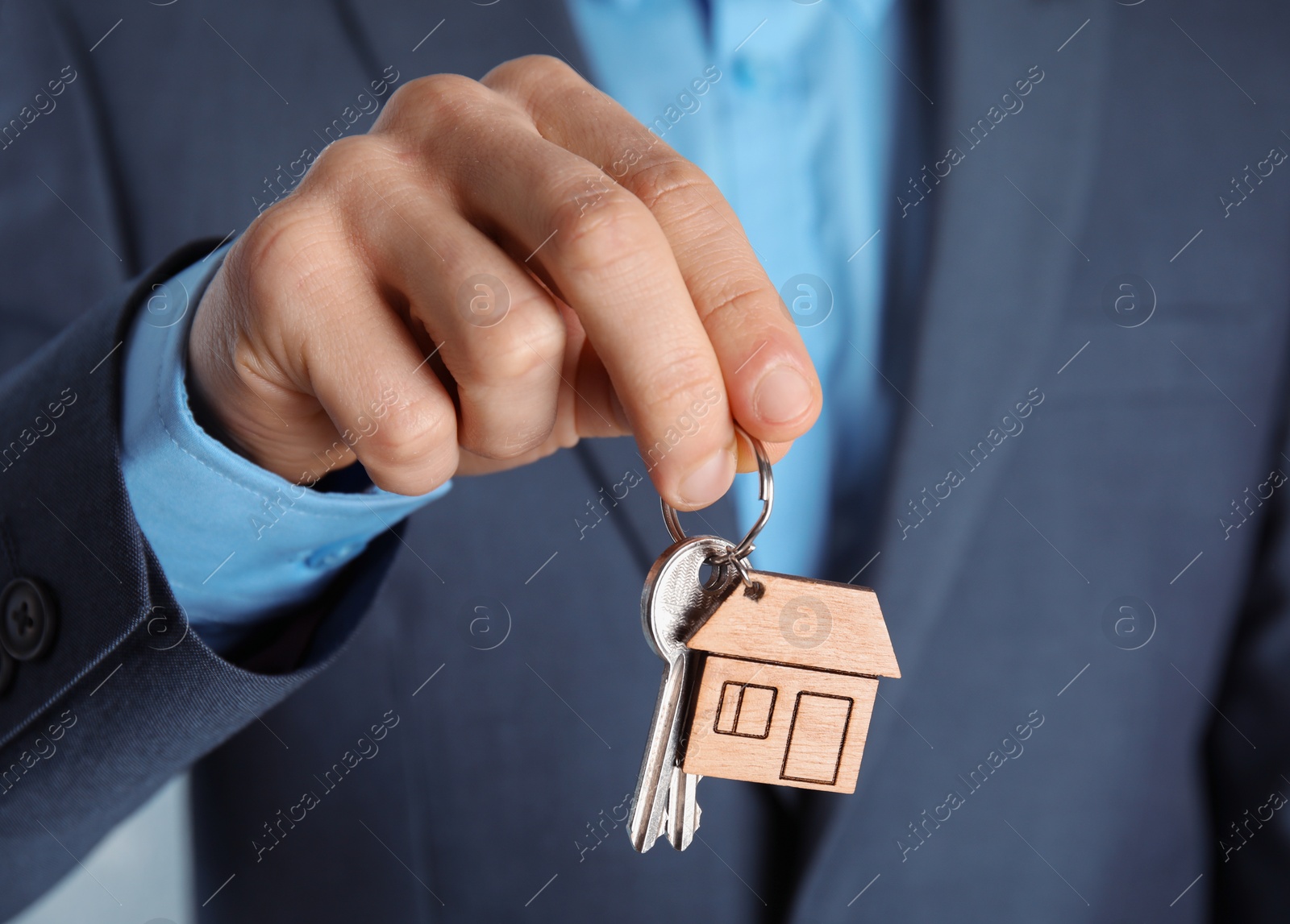 Photo of Young man holding house key with trinket, closeup