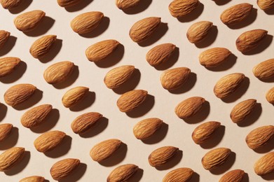 Delicious raw almonds on beige background, flat lay