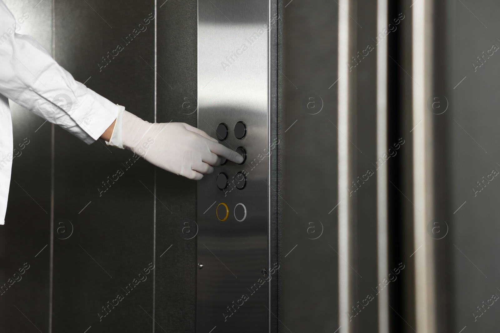 Photo of Woman wearing medical glove choosing floor in elevator, closeup. Protective measure