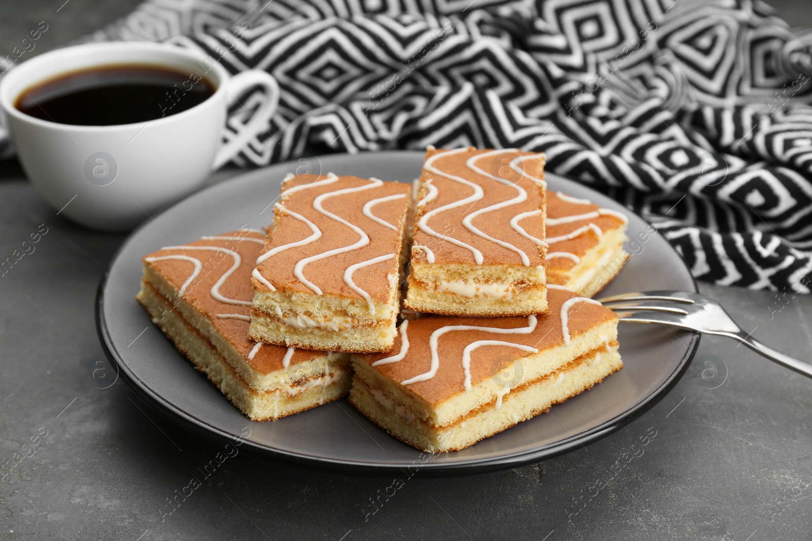 Photo of Tasty sponge cakes and hot drink on grey table