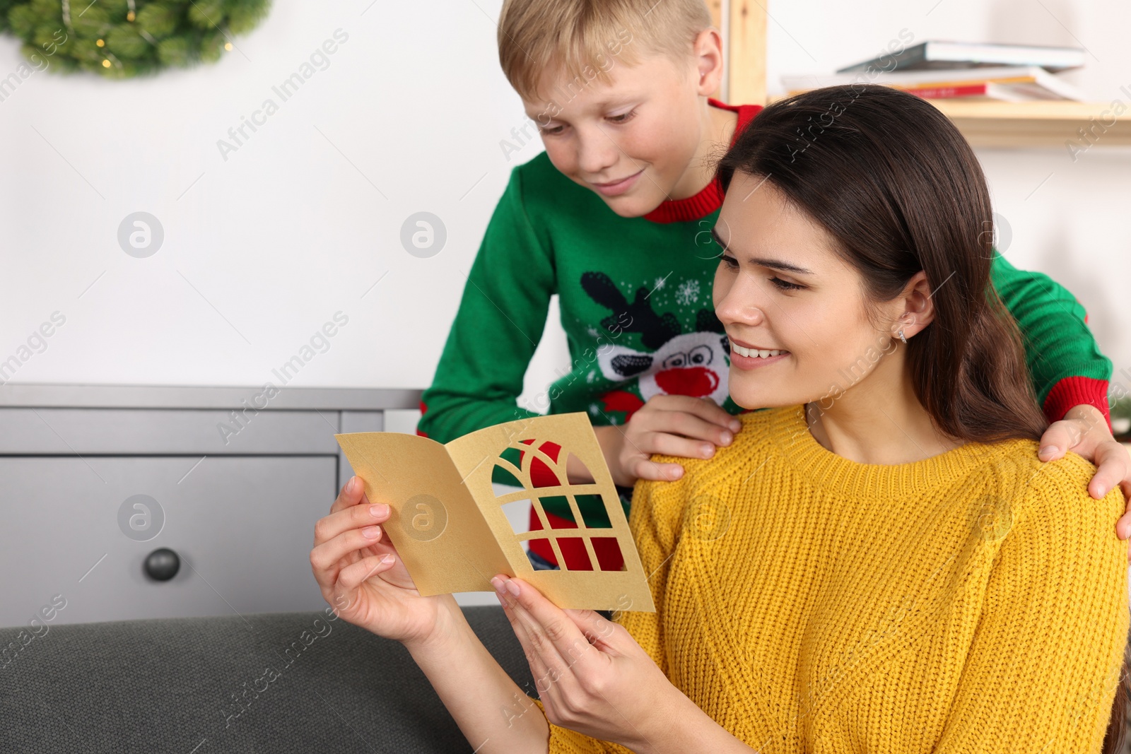 Photo of Happy woman receiving greeting card from her son at home