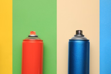 Cans of different spray paints on color background, flat lay with space for text. Graffiti supplies