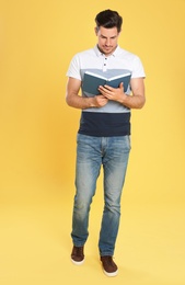 Photo of Handsome man reading book on color background