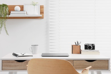 Photo of Home office. Stylish workplace with laptop and stationery on white desk indoors. Space for text