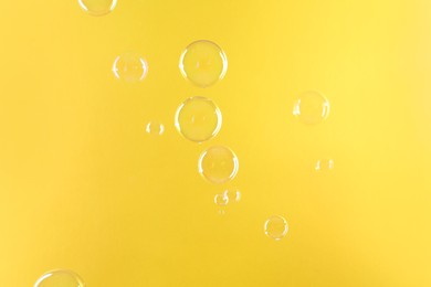 Beautiful transparent soap bubbles on yellow background