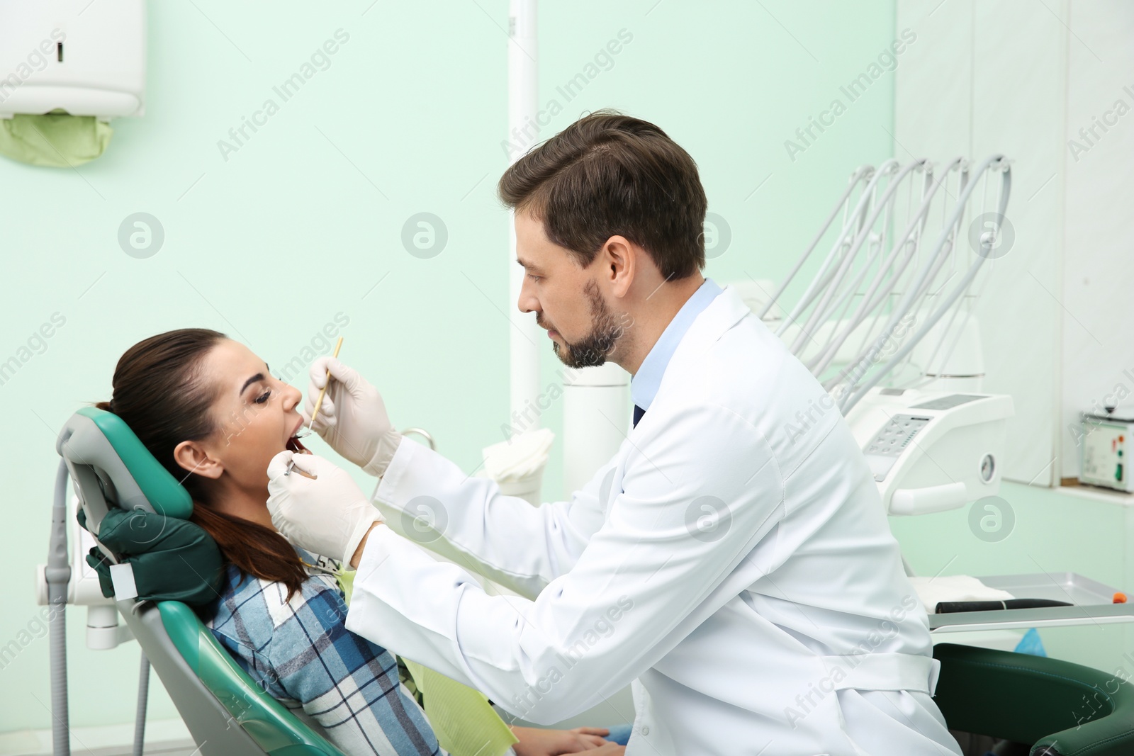 Photo of Professional dentist working with patient in modern clinic