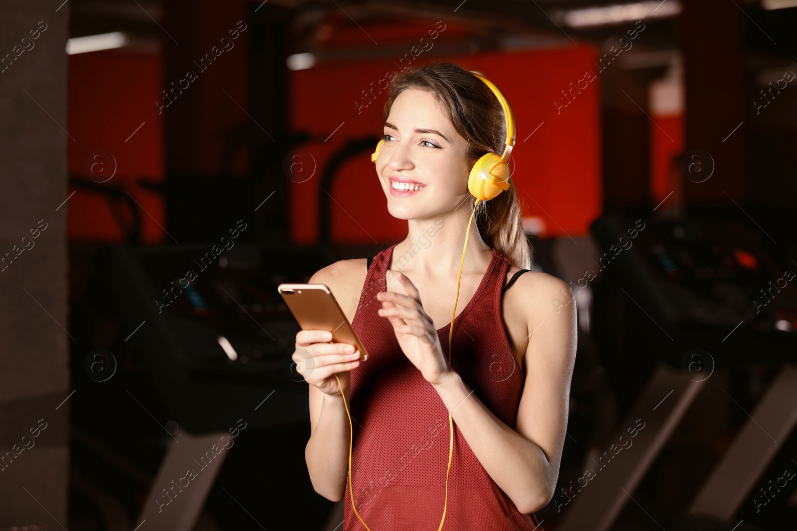 Photo of Young woman with headphones listening to music on mobile device at gym