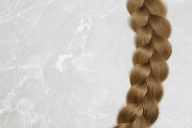 Braided hair on grey background, top view with space for text