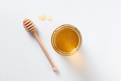 Photo of Tasty honey in glass jar and dipper on white background, top view