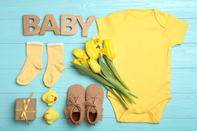 Photo of Flat lay composition with child's clothes and word Baby on light blue wooden table