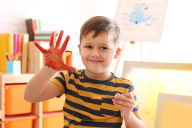 Photo of Cute little child with painted palm in room