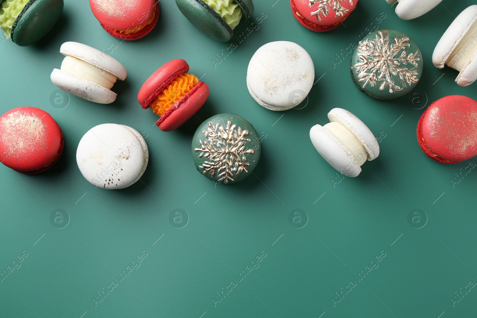 Photo of Beautifully decorated Christmas macarons on green background, flat lay. Space for text