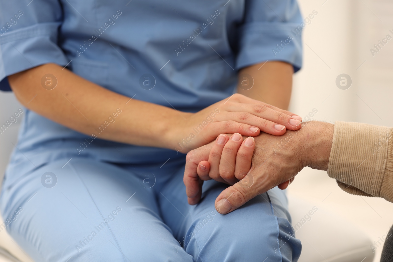 Photo of Nurse supporting elderly patient indoors, closeup view