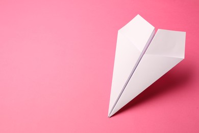 Handmade white paper plane on pink background, space for text