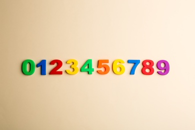 Colorful magnetic numbers on beige background, flat lay