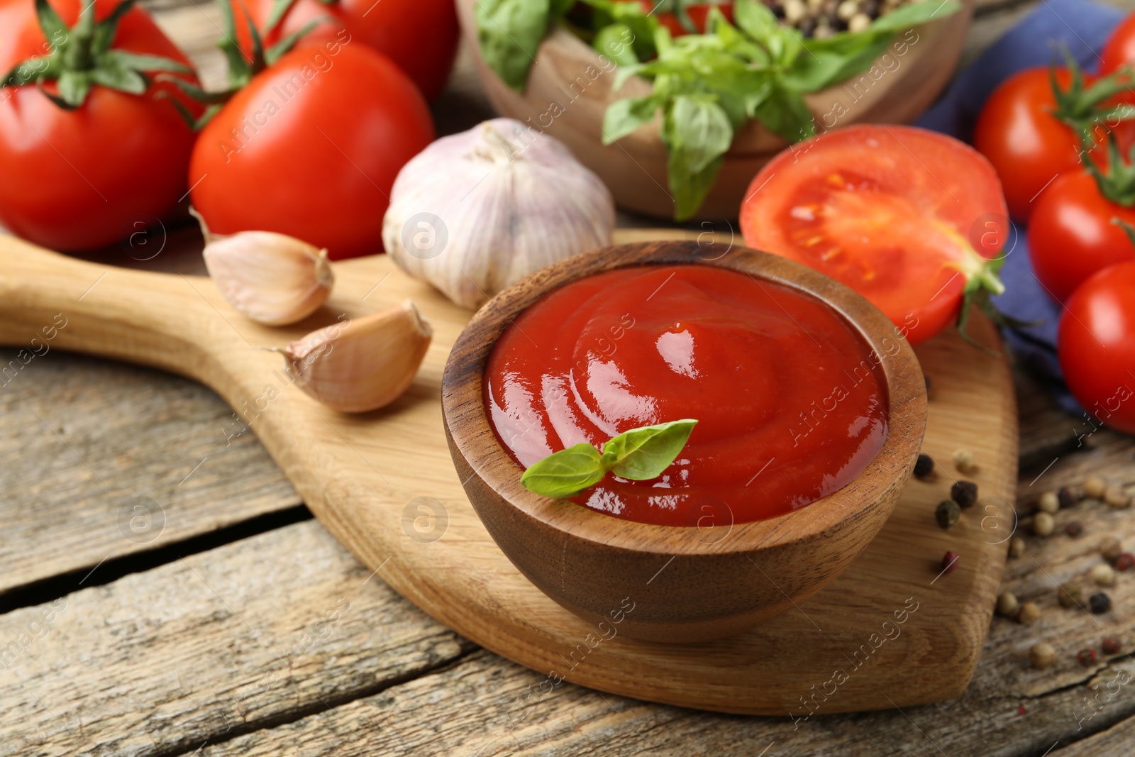 Photo of Tasty ketchup, fresh tomatoes, basil and spices on wooden table