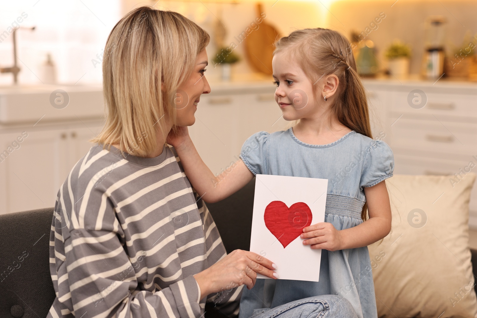 Photo of Little daughter congratulating her mom with greeting card at home. Happy Mother's Day