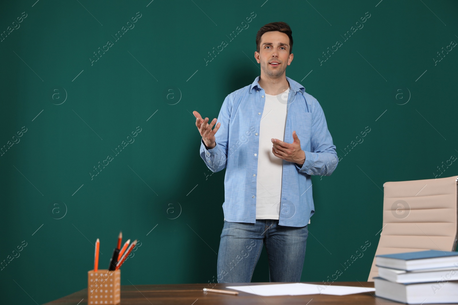 Photo of Portrait of male teacher near table in classroom. Space for text