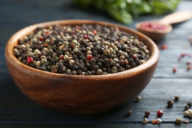 Photo of Mix of peppercorns in bowl on dark wooden table, closeup