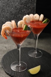 Tasty shrimp cocktail with sauce in glasses and lime on grey table