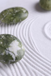 Photo of Zen concept. Stones and pattern on white sand, closeup