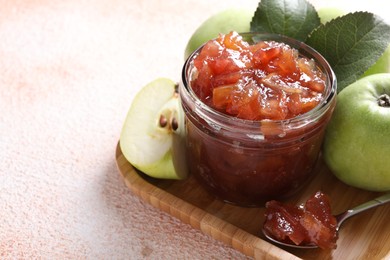 Photo of Glass jar of delicious apple jam and fresh fruits on light table, space for text