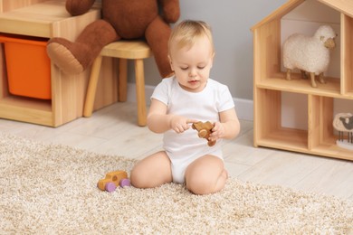 Photo of Children toys. Cute little boy playing with wooden car on rug at home