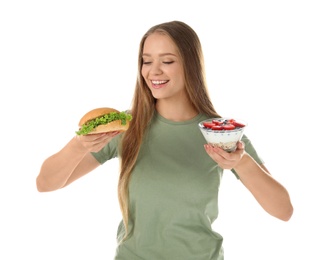 Photo of Young woman with tasty dessert and hamburger on white background. Healthy diet