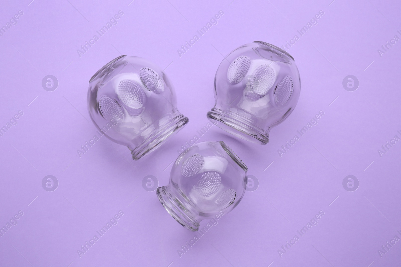 Photo of Glass cups on violet background, flat lay. Cupping therapy