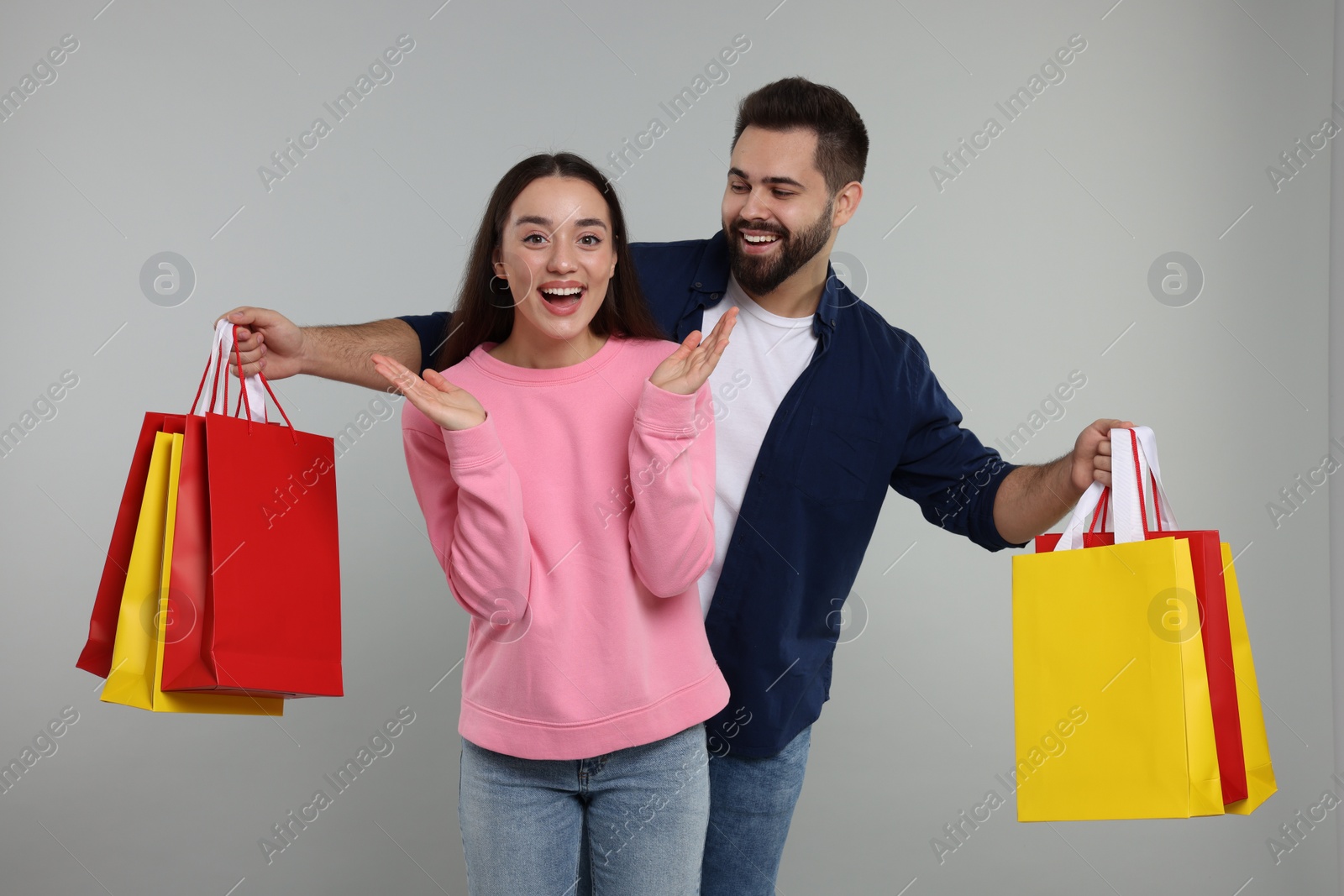 Photo of Excited couple with shopping bags on grey background