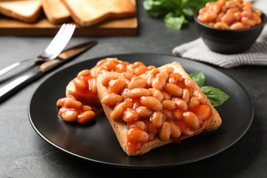 Photo of Toasts with delicious canned beans on black table
