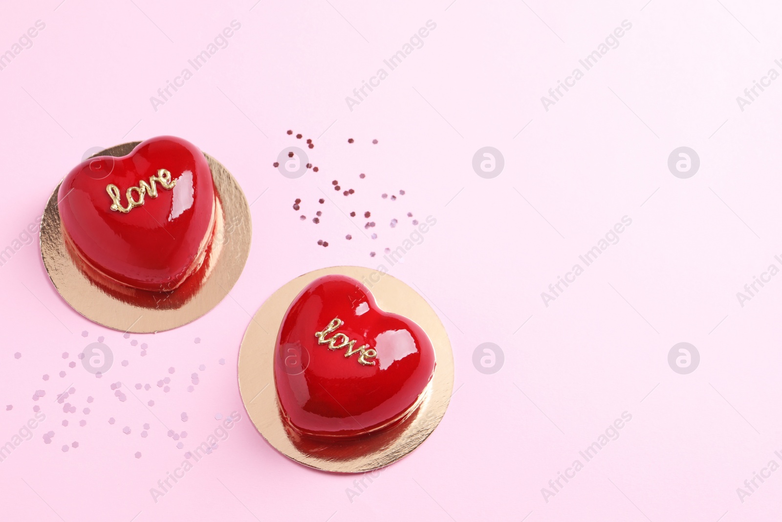 Photo of St. Valentine's Day. Delicious heart shaped cakes on light pink background, flat lay. Space for text