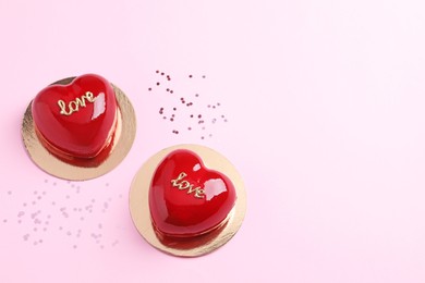 Photo of St. Valentine's Day. Delicious heart shaped cakes on light pink background, flat lay. Space for text