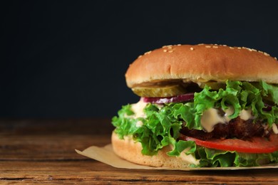 Photo of Delicious burger with beef patty and lettuce on wooden table, closeup. Space for text
