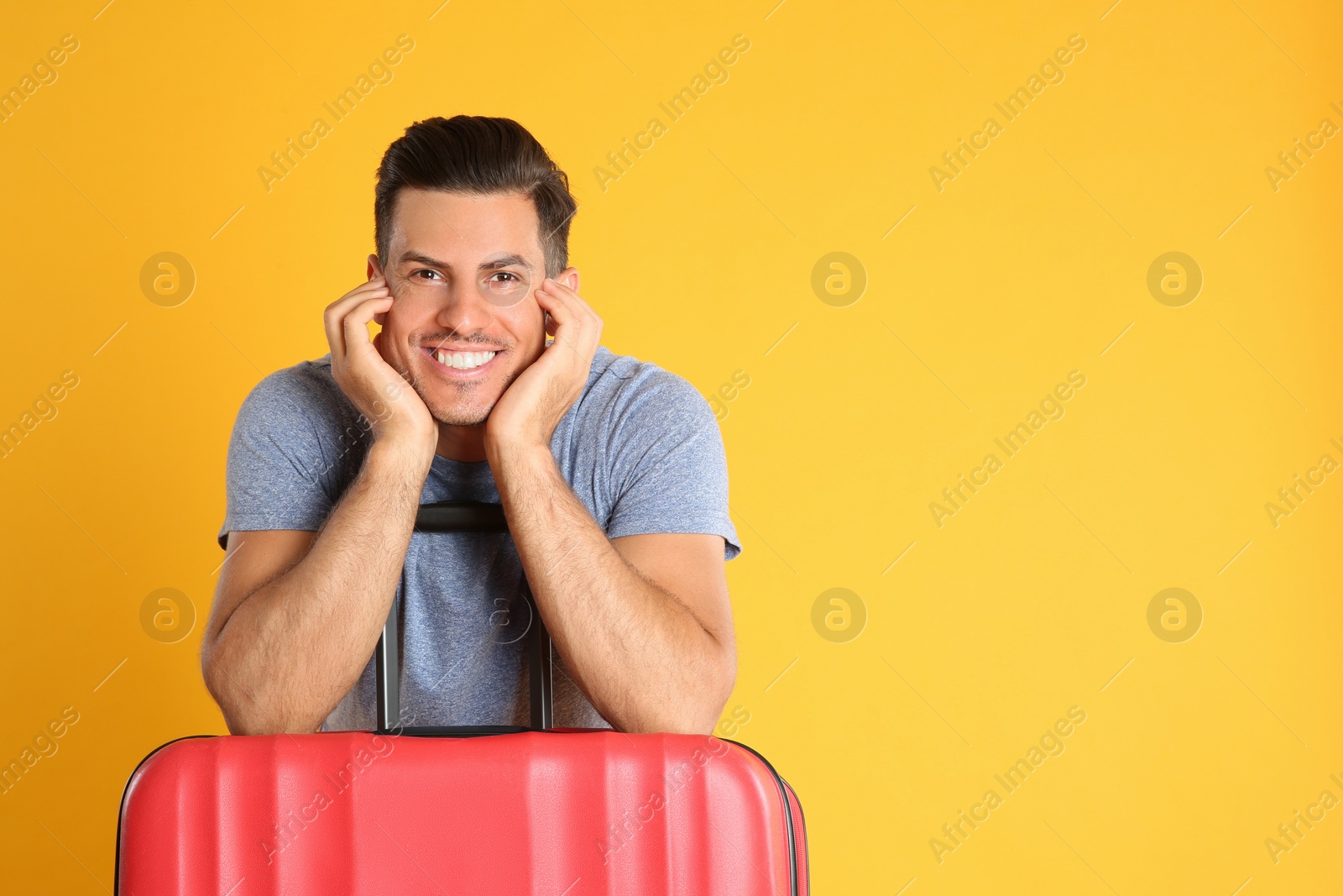 Photo of Handsome man with suitcase for summer trip on yellow background. Vacation travel