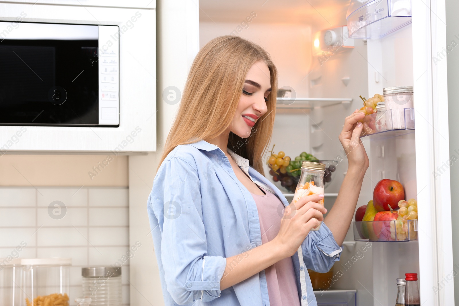 Photo of Young woman with yogurt in kitchen