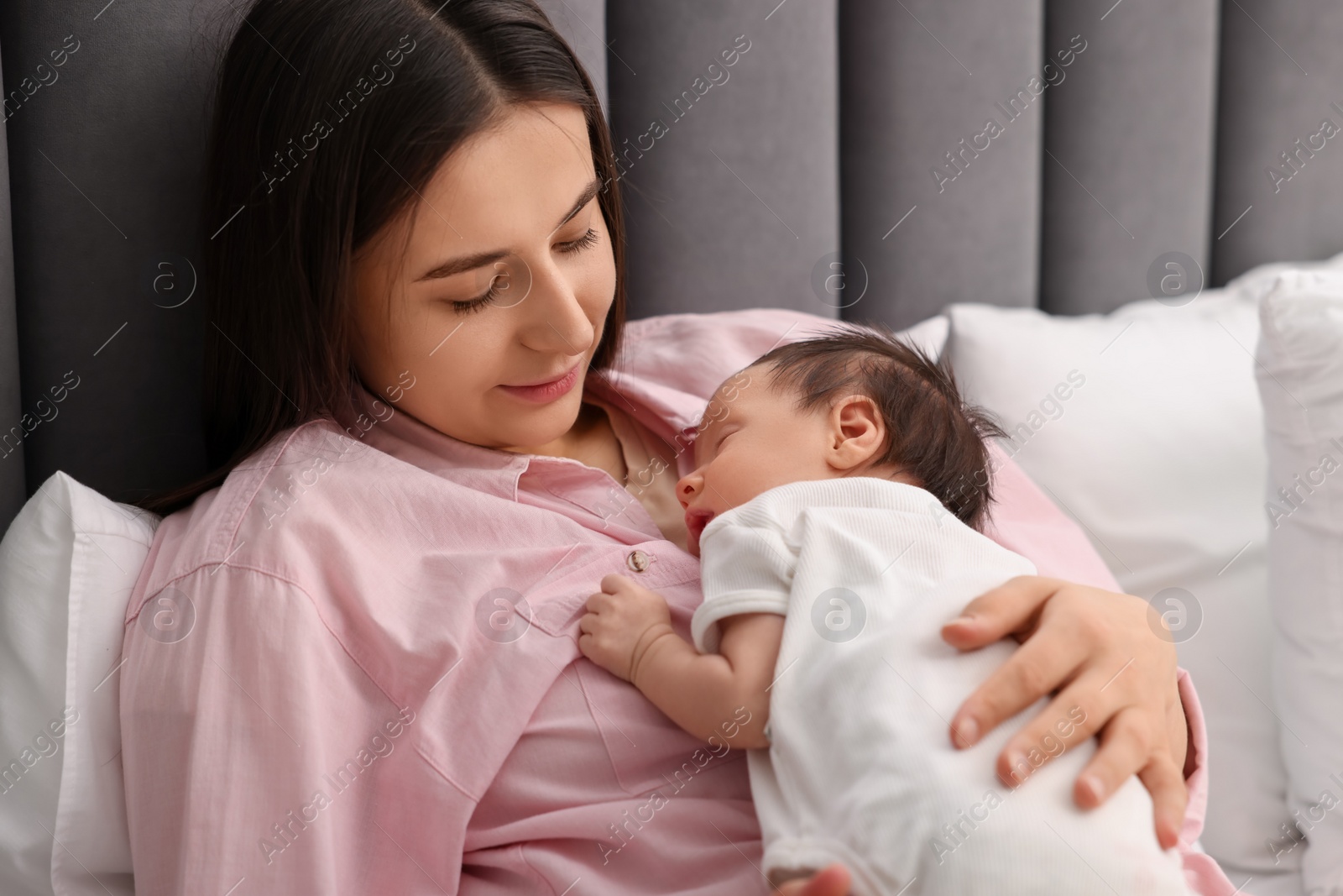 Photo of Mother with her sleeping newborn baby in bed