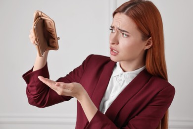 Photo of Upset woman with empty wallet near white wall