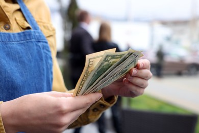 Waitress holding tips in outdoor cafe, closeup