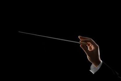 Photo of Professional conductor with baton on black background, closeup