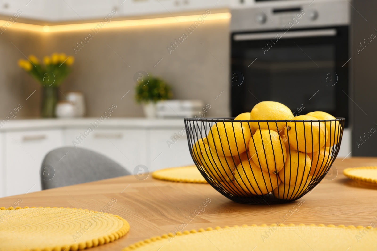 Photo of Spring interior. Bowl of lemons on wooden table in kitchen, space for text