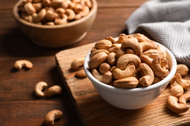 Photo of Tasty cashew nuts in bowl on table